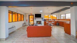 Un hall de hotel con sofá, televisor, chimenea y una zona de cocina.