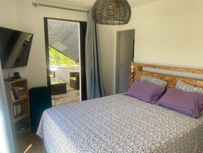 Une chambre à coucher avec un lit, une télévision, une bibliothèque et une vue sur l’extérieur.