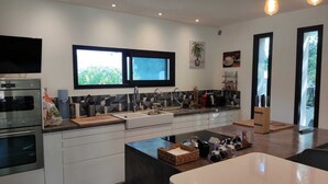 Una cocina moderna con horno integrado, un lavamanos y un amplio ventanal.