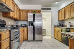 A kitchen with wooden cabinets, stainless steel appliances, granite countertops, and a tiled floor. - 3 Mi to El Paso Mission Trail! Group-Ready Escape (Socorro)