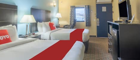 A hotel room with two beds, a desk, a TV, and a window with curtains.