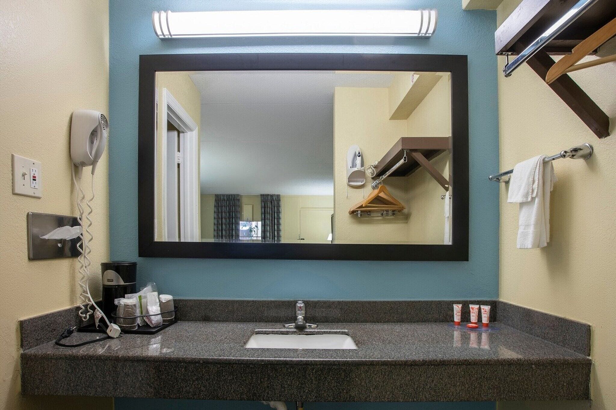 Een badkamer met een wastafel, spiegel, haardroger en handdoekhouder.