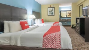 A hotel room with two beds, a TV, a desk, and a bathroom.