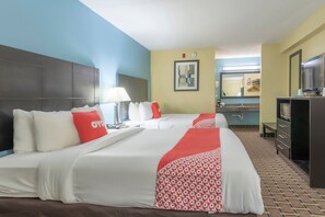 A hotel room with two beds, a TV, a desk, and a bathroom.