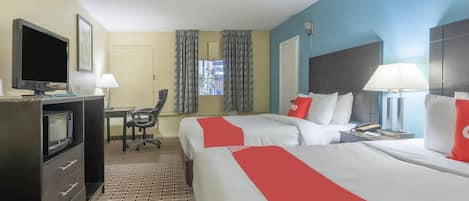 A hotel room with two beds, a desk, a television, and a window with curtains.