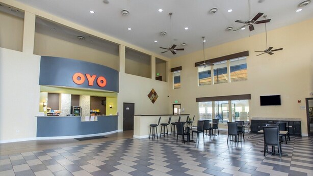 A spacious lobby with a reception desk, multiple seating areas, and ceiling fans.