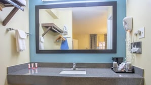 Un baño con un espejo grande, un lavabo, un perchero para toallas y un secador de pelo.