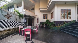 A courtyard with a dining area, chairs, a table, and a staircase. - Hotel Danau Tjokro 3 By ARBA (Cisarua)