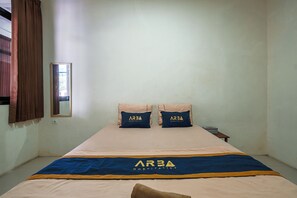 Ein Hotelzimmer mit einem Bett, zwei mit einem Logo versehene Kissen, einem Nachttisch und einem Fenster mit Vorhängen.