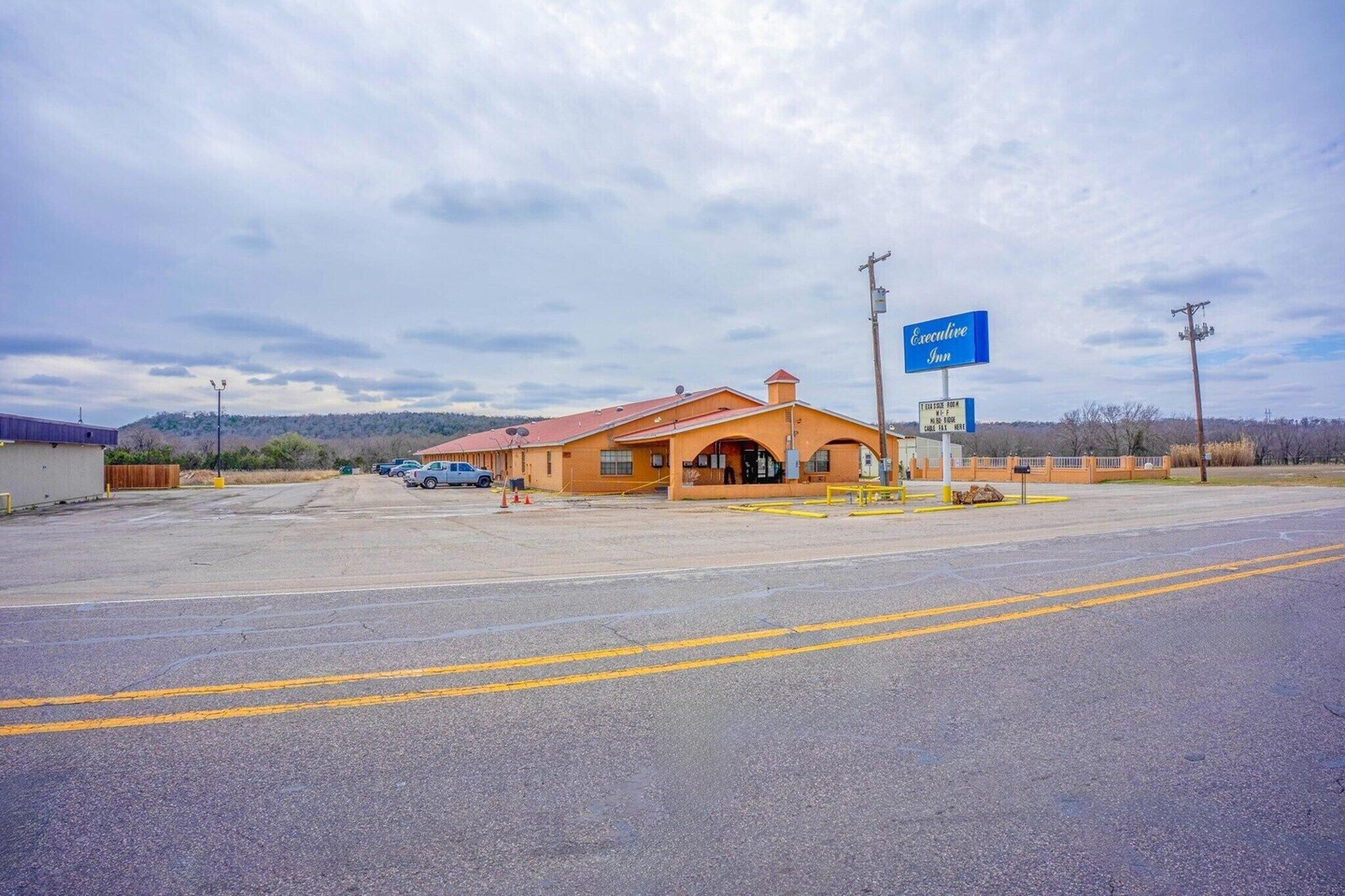 A building with a red roof, a blue sign reading 'Executive,' and a parking lot in front.