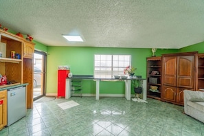 Una cocina con refrigerador, pileta, ventana y estantería.