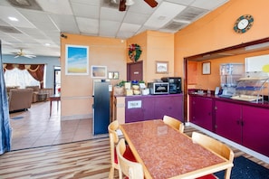 A hotel room with a dining area, a refrigerator, a microwave, a trash bin, and a clock on the wall. - 2 Full Bed | Smoking|Columbia (Columbia)