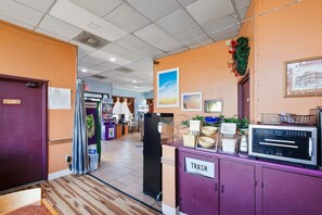 Un hall d’hôtel avec une poubelle, un réfrigérateur et un four à micro-ondes sur un comptoir.