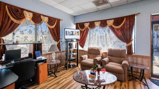 A room with a sofa, armchairs, a desk with a computer, a TV, and a small table with a vase. - King Bed Smoking with Jetted Tub (Columbia)