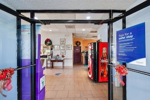 A hotel entrance with a reception desk, framed pictures on the wall, and a Coca-Cola vending machine. - King Bed |Non Smoking|Columbia (Columbia)