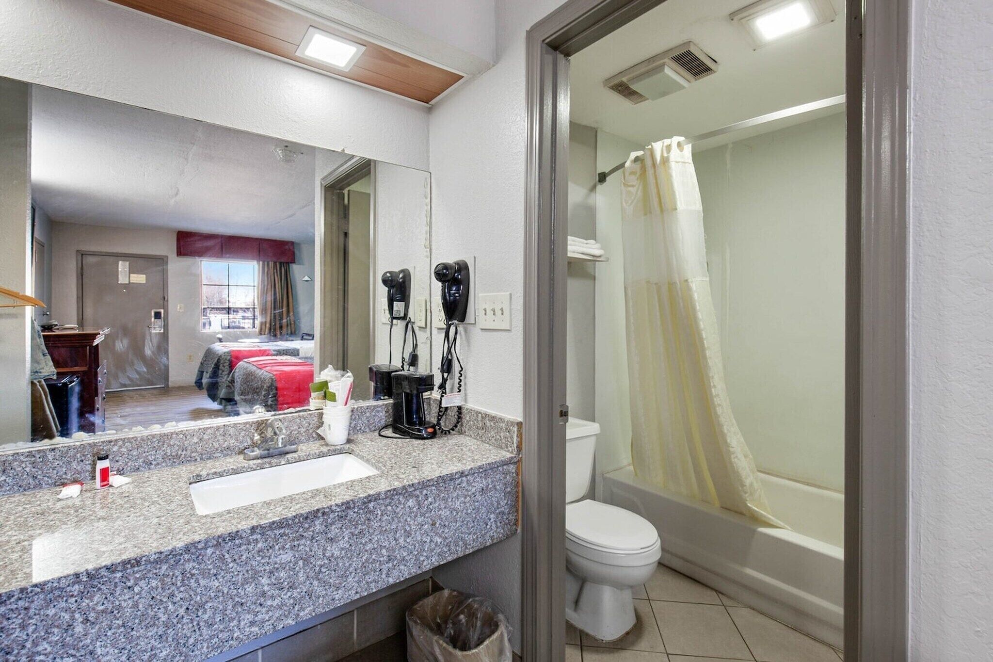 A bathroom with a sink, mirror, hairdryer, and shower curtain.
