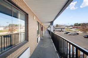 A covered outdoor corridor with a brick building, large windows, and a parking lot visible in the background. - 2 Full Beds | Non Smoking (Columbia)