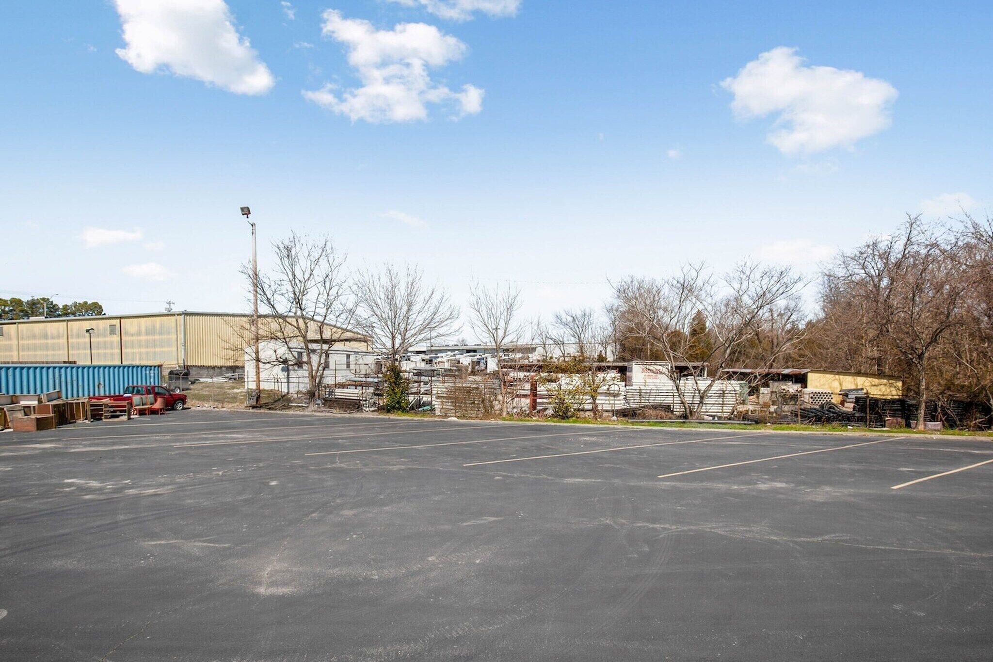 An empty parking lot with a large industrial building in the background.