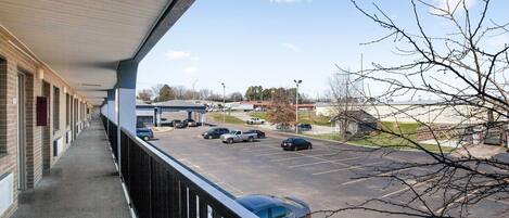 A building with a covered balcony overlooking a parking lot with several cars.