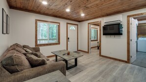 Una sala de estar con techo de madera, un sofá, una mesa y un televisor.
