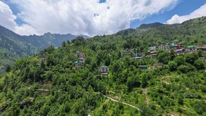 A mountainous area with buildings scattered across the hillside. - Aranya Retreat Himachal (Manali)