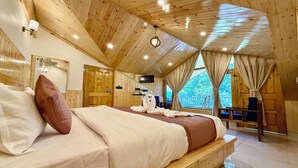 A wooden-paneled room with a bed, a TV, and a view of the outdoors. - Aranya Retreat Himachal (Manali)