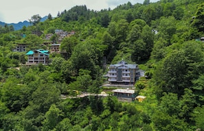 A hillside village with multiple buildings surrounded by dense greenery.