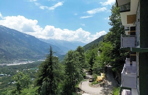 Eine gebirgige Landschaft mit einer Straße, Gebäuden und viel Grün.
