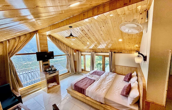 Ein Schlafzimmer mit Holzbalkendecke, einem Bett, einem Fernseher und einem Balkon mit Blick.