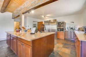 Una cocina amplia con una isla grande, electrodomésticos integrados y piso de piedra.