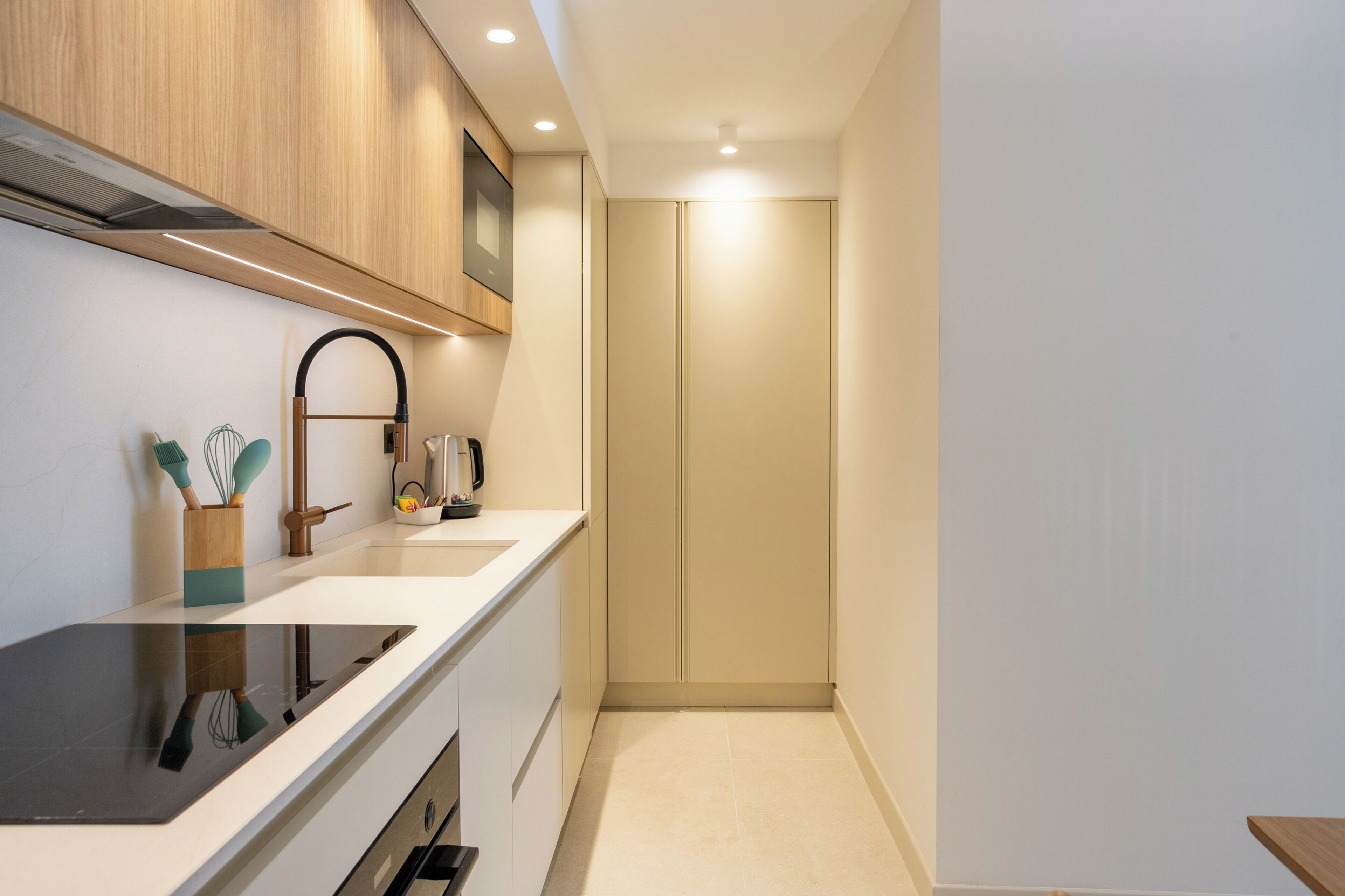 A modern kitchen with a black stove, wooden cabinets, a sink, and a coffee maker.