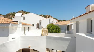A white building with a tiled roof, a staircase, and a small garden area.