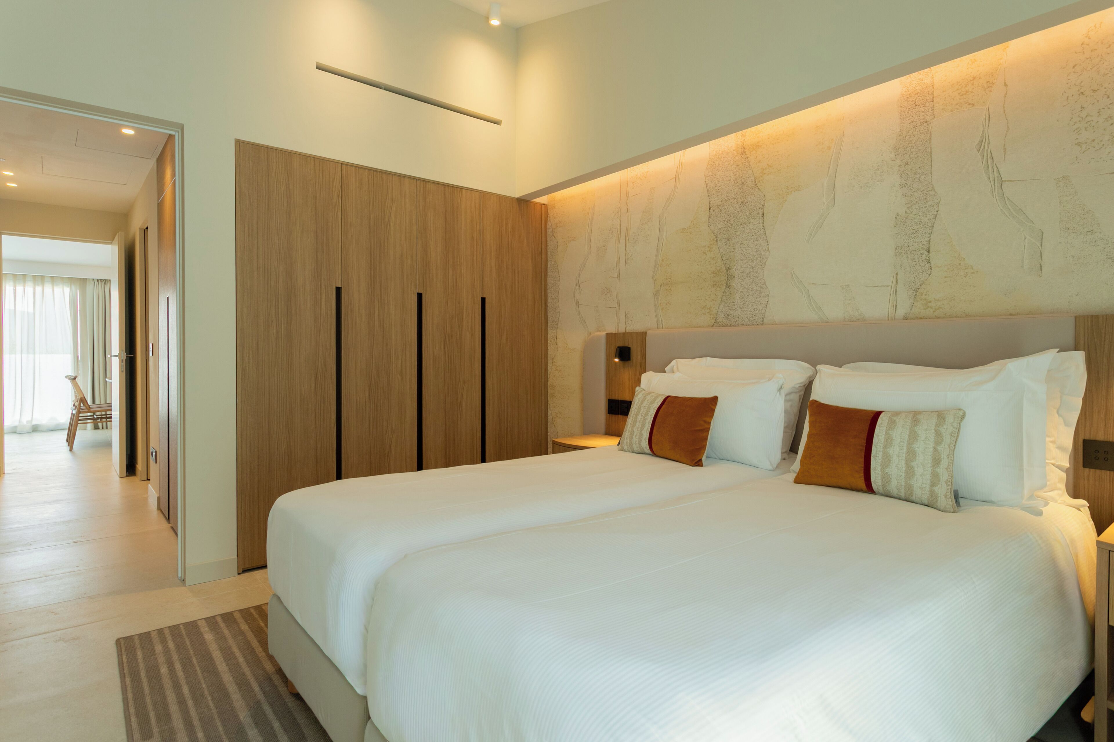 Une chambre d’hôtel moderne avec un grand lit, une armoire en bois et un mur décoratif.