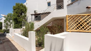 Un bâtiment blanc avec un escalier, une clôture en bois et de la verdure.