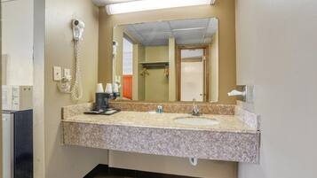 A bathroom with a granite countertop, a sink, a mirror, a hairdryer, and a towel rack.