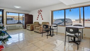 A room with a large window, a small table with chairs, a Christmas tree, and a wall decoration. - 2 Queen Beds|Non-Smoking (Devils Lake, ND)