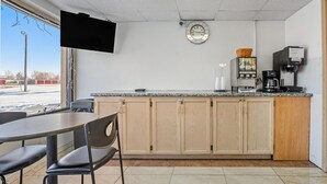 A small café with a counter, a television mounted on the wall, a clock, and a coffee machine. - 2 Queen Beds|Non-Smoking (Devils Lake, ND)