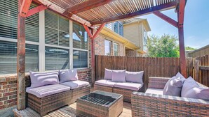 A covered patio with wicker furniture, a glass coffee table, and a wooden fence. - Lewisville Home w/ Pool Access: Walkable Location (Lewisville)