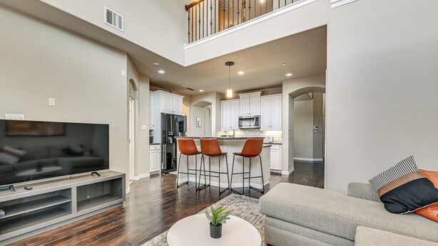 A spacious living room with a flat-screen TV, a gray sofa, and a coffee table. - Lewisville Home w/ Pool Access: Walkable Location (Lewisville)