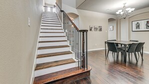 A staircase with wooden steps and black railings, leading to a dining area with a table and chairs. - Lewisville Home w/ Pool Access: Walkable Location (Lewisville)
