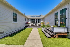 Ein Haus mit überdachter Terrasse, einem Betonweg und einem kleinen Garten.