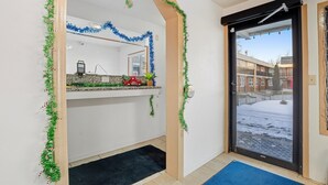 A room with a large window, a door, and a counter with a plant. - King Bed|Non-Smoking (Devils Lake, ND)