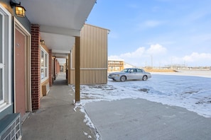 Un edifici amb un passatge cobert, parets de maó i un cotxe estacionat en una zona nevada.