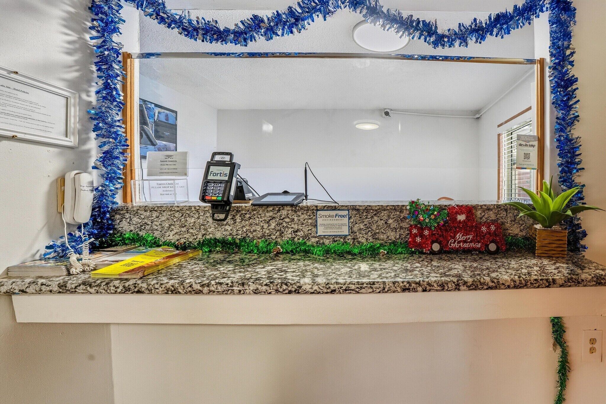 Ein Empfangstresen mit einem Fortis-Kartenlesegerät, einem Schild mit der Aufschrift 'Smoke Free' und einer Weihnachtsdekoration.