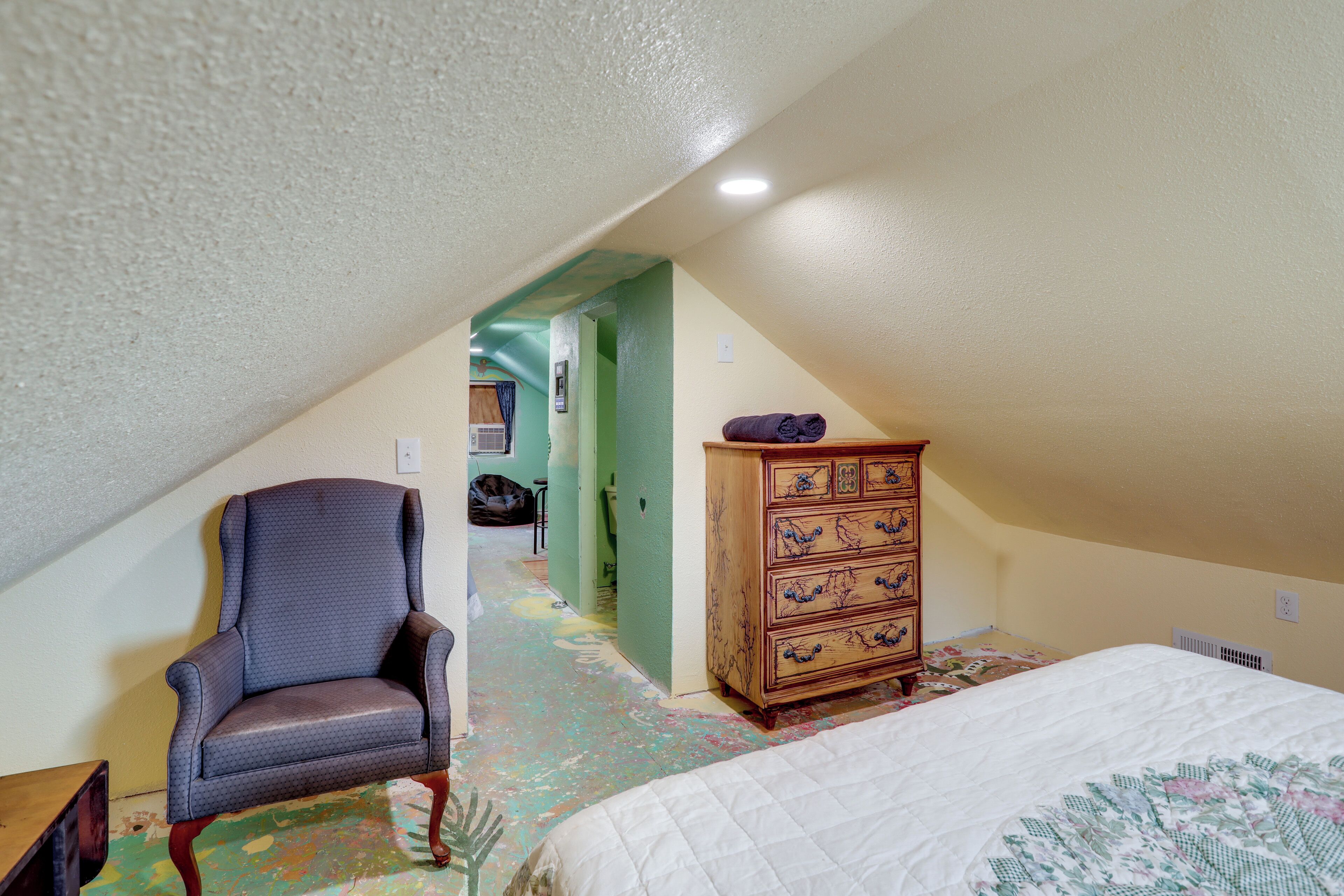 Une chambre à coucher comprenant un lit, une commode, une chaise et un couloir menant à une autre pièce.