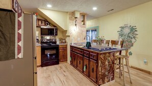 A kitchen with wooden cabinets, a refrigerator, a stove, and a sink. - Home Near Eleven Point River & Nat'l Forest! (Alton)