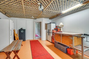 Une pièce avec un plafond en bois, un établi, un tapis rouge et des armoires de rangement.