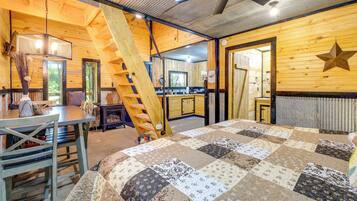 Une pièce chaleureuse avec un décor intérieur en bois, un lit à couvre-lit matelassé, une table à manger et un escalier.