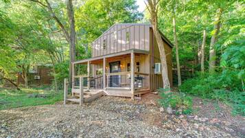 Une cabane en bois avec un porche, entourée d’arbres.