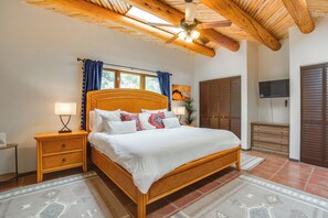 A bedroom with a wooden bed, nightstands, a ceiling fan, a TV, and a wardrobe.